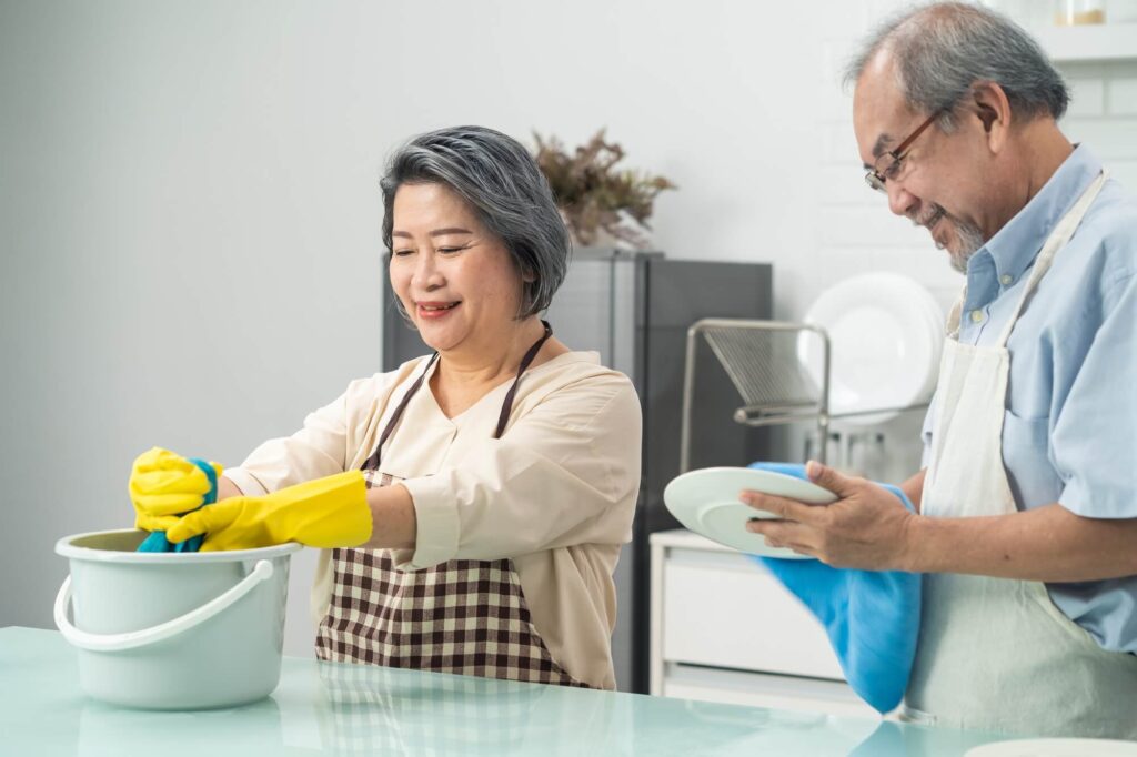 asian young aged housewife twisting wet rag to clean the kitchen counter